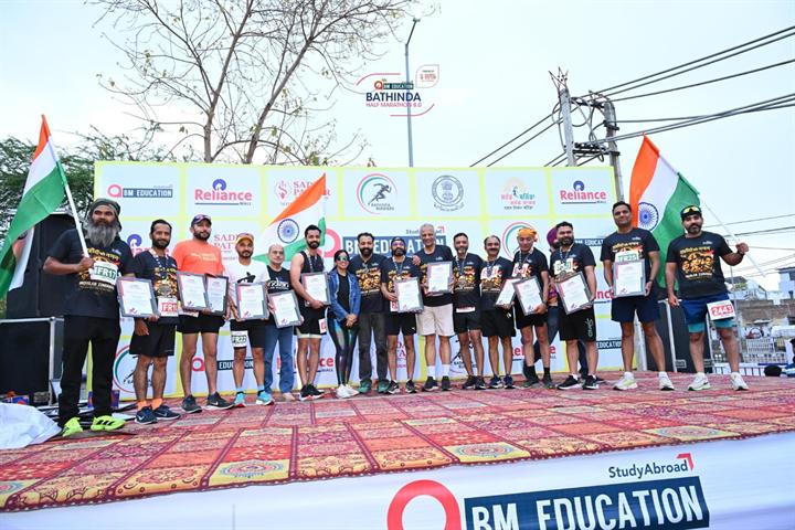 Runners hold the Indian flag and certificates on the Bathinda Half Marathon 8.0 stage
