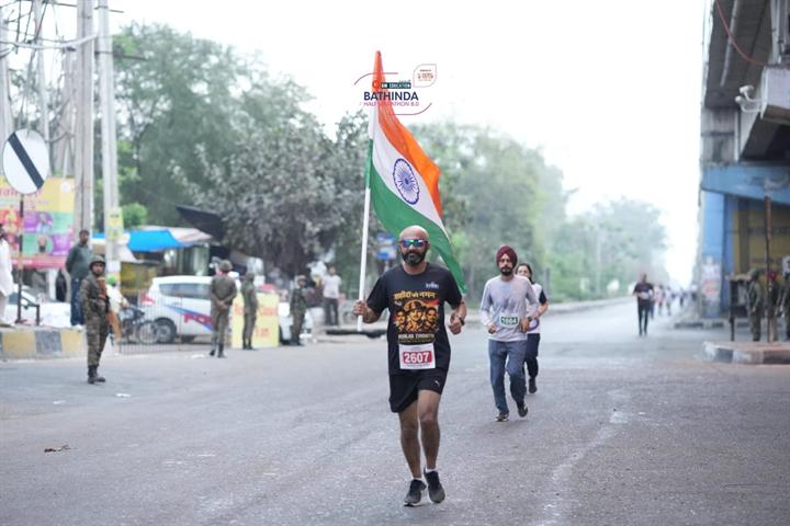 A runner on course with the Indian flag behind at Bathinda Half Marathon 8.0