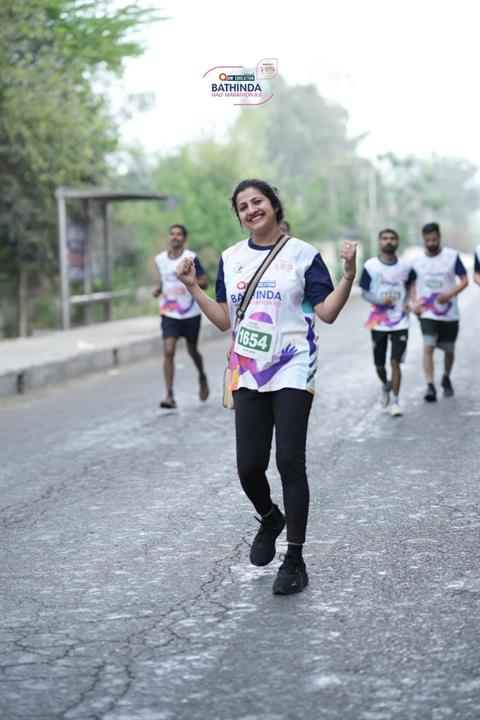 A smiling woman runner on the Bathinda Half Marathon 8.0 course