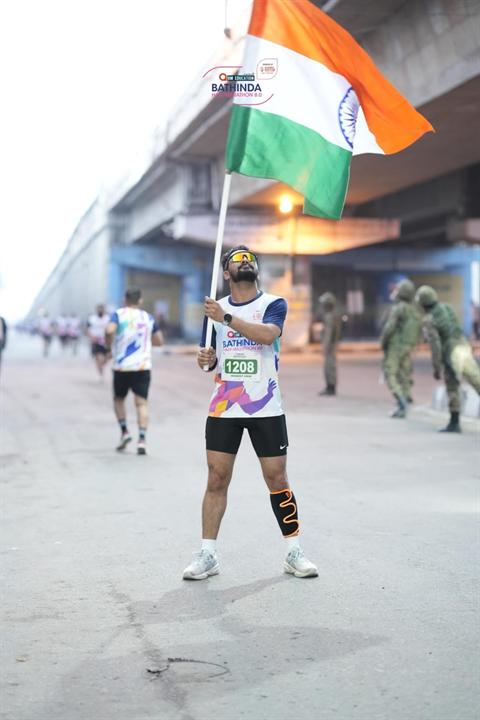 A runner carries the Indian flag under the flyover at Bathinda Half Marathon 8.0